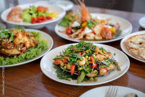 a Thai food Seafood fried in a spicy sauce in white circle dish on wooden table background.