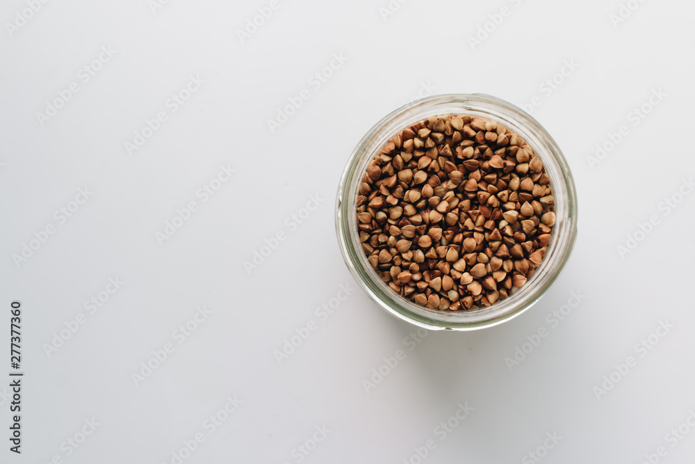 Raw buckwheat in glass on white background Raw buckwheat in glass on white background