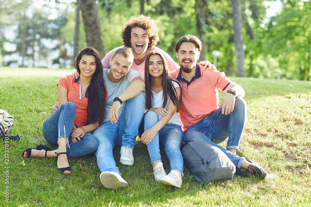 A group of friends laughing hugging sitting in a park