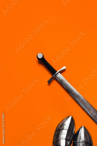 Sabatons and a sword on an orange background. photo