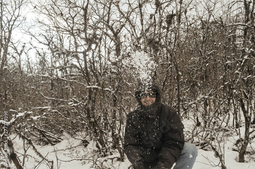 Smiling happy joyful Portrait of a Man wearing a black pullover jacket enjoying first snow playing and throwing snowball in air. Enjoy Snowing day view in winter. Rural village Jammu and Kashmir India
