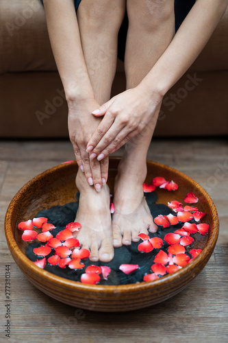 Female feet at spa pedicure procedure, Spa foot massage, Massage of woman's foot in spa salon, Beauty treatment concept, Female legs in water decoration flowers and getting massage