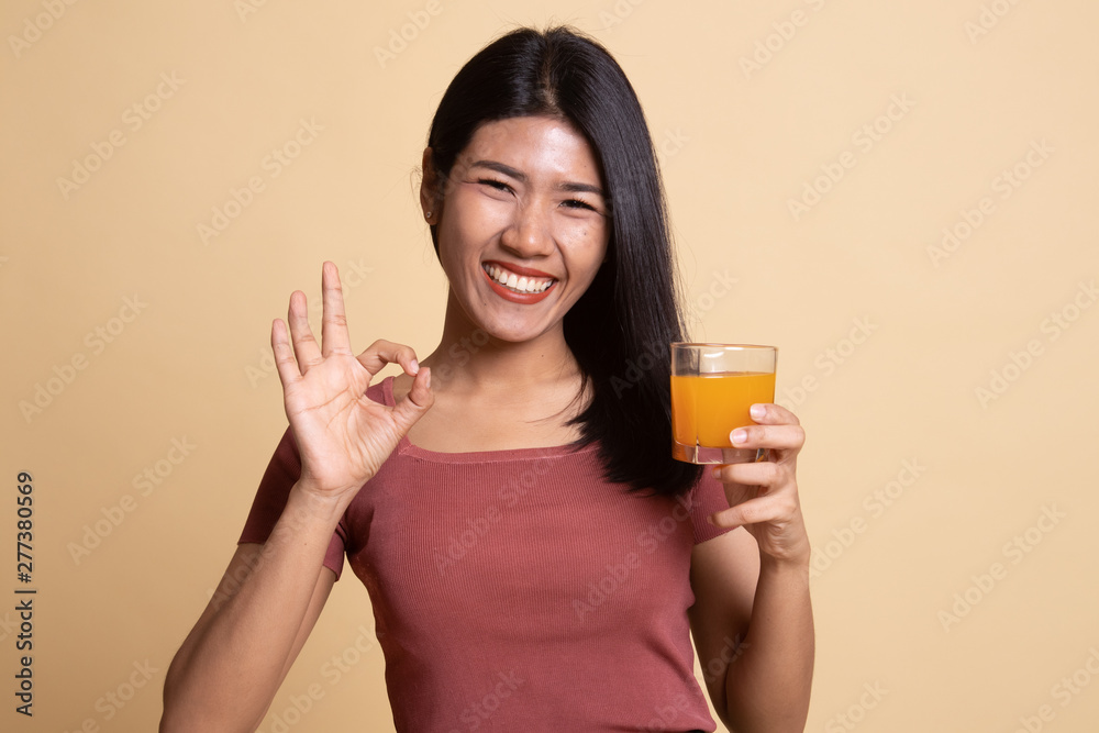 Young Asian woman drink orange juice show OK sign. Young Asian woman drink orange juice show OK sign.