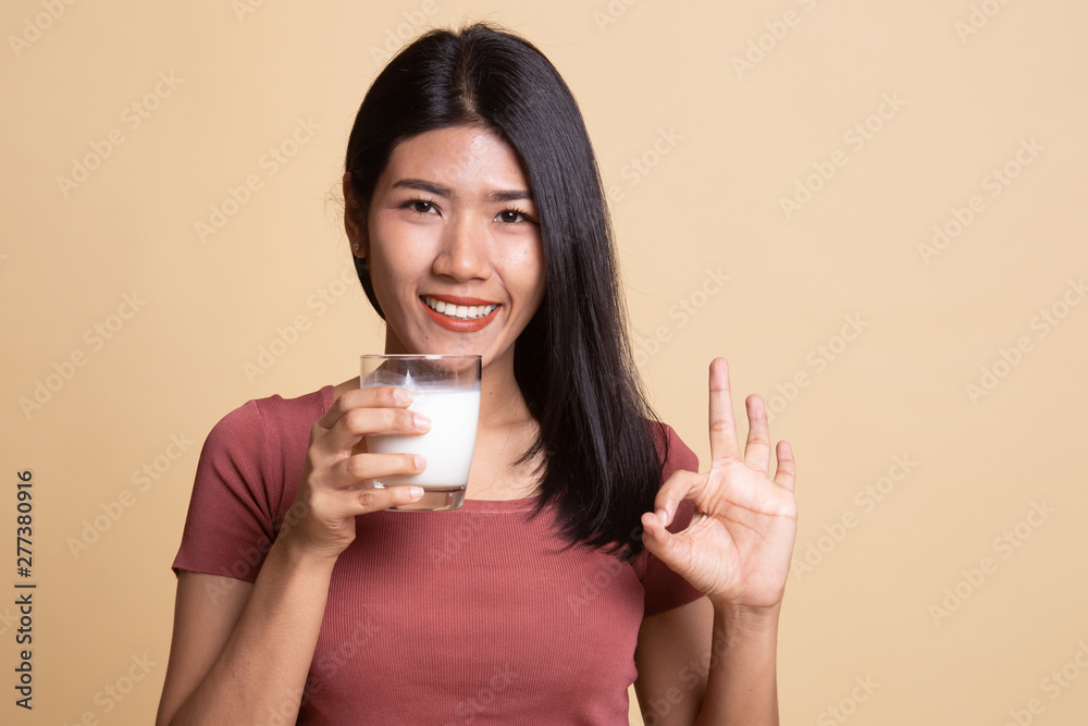Healthy Asian woman drinking a glass of milk show OK sign. Healthy Asian woman drinking a glass of milk show OK sign.
