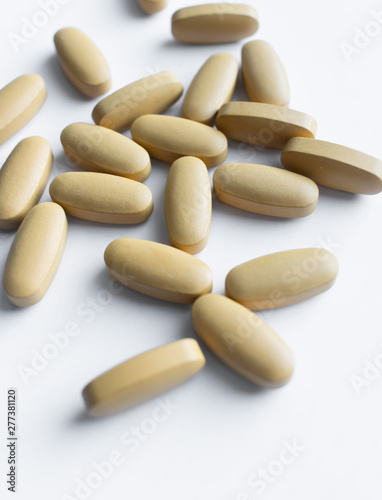 Scatterded yellow pills on white background
