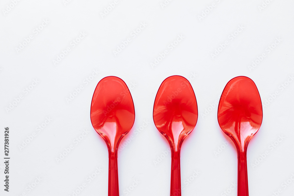 Red plastic spoons flat lay on white background Red plastic spoons flat lay on white background