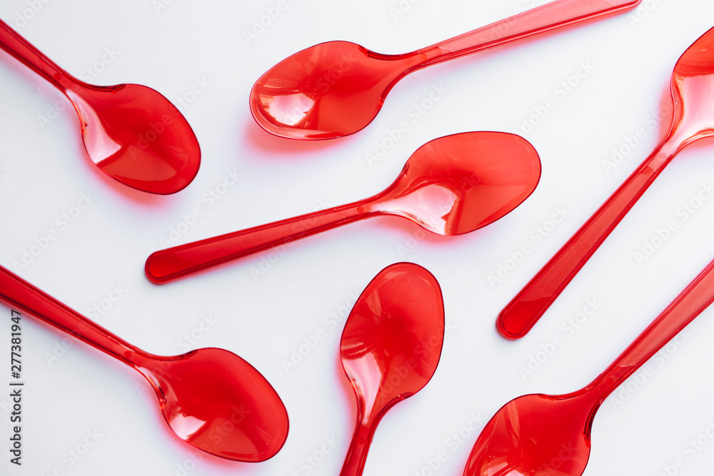 Red plastic spoons flat lay on white background Red plastic spoons flat lay on white background