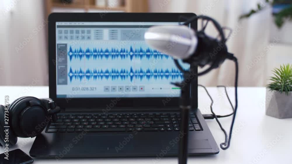 post production and technology concept - sound editor program on laptop computer, microphone, headphones and smartphone on table at home office post production and technology concept - sound editor program on laptop computer, microphone, headphones and smartphone on table at home office