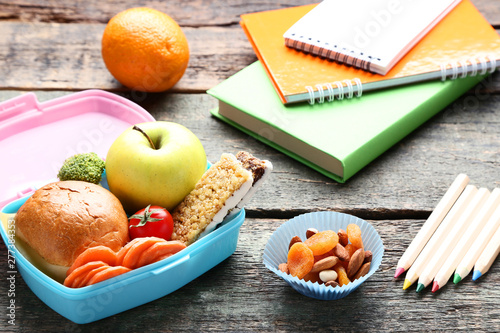 School lunch box with sandwich and pencils on wooden table