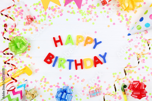 Text Happy Birthday by plastic letters with decorations and confetti on white background