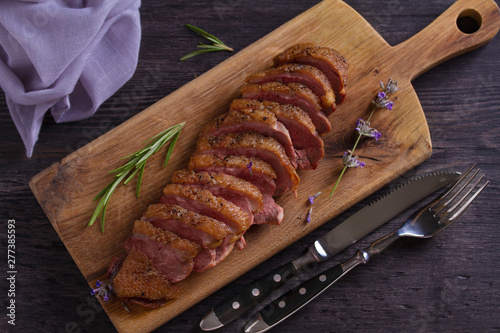 Sliced duck breast, lavender honey and rosemary on serving board