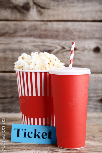 Red paper cup with popcorn in bucket and word Ticket on wooden table