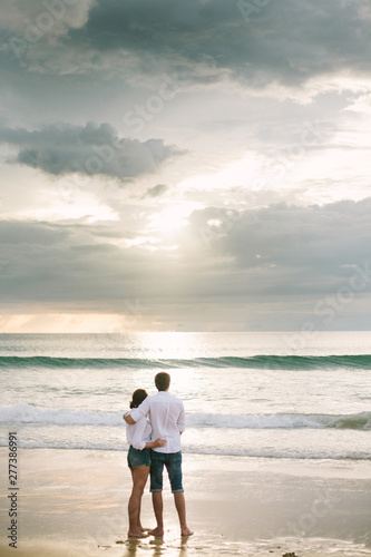 A man hugs a woman. They stand and look at the sea. Solitude together.