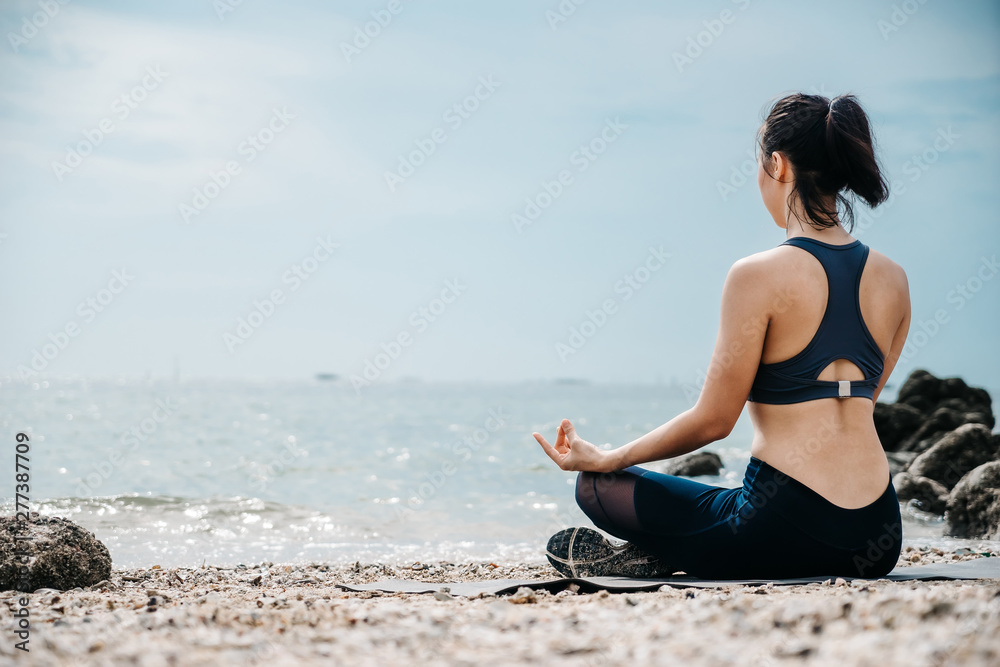 Asian caucasian woman practicing yoga at seashore at morning of her some weekend holiday.