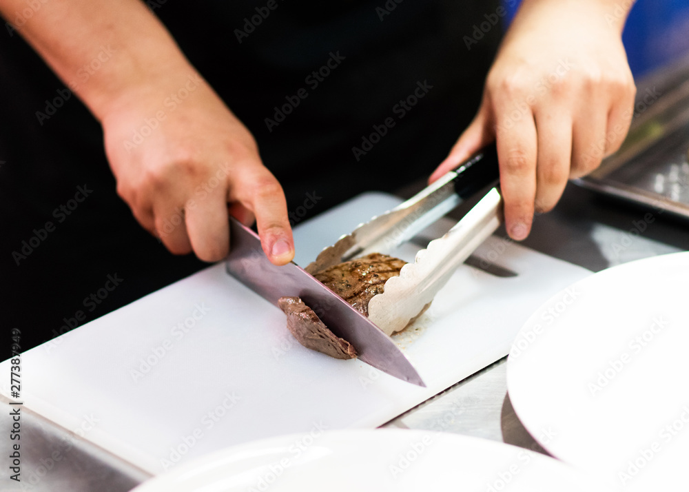 chef with knife and cutting tasty grilled steak, Chef preparing meal in the kitchen chef with knife and cutting tasty grilled steak, Chef preparing meal in the kitchen