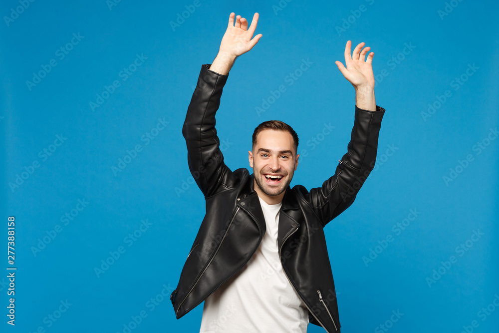 Stylish young happy bearded man in black leather jacket white t-shirt doing winner gesture say Yes isolated on blue wall background studio portrait. People sincere emotions concept. Mock up copy space