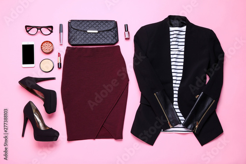 Modern women's clothes with accessories and makeup cosmetics on pink background