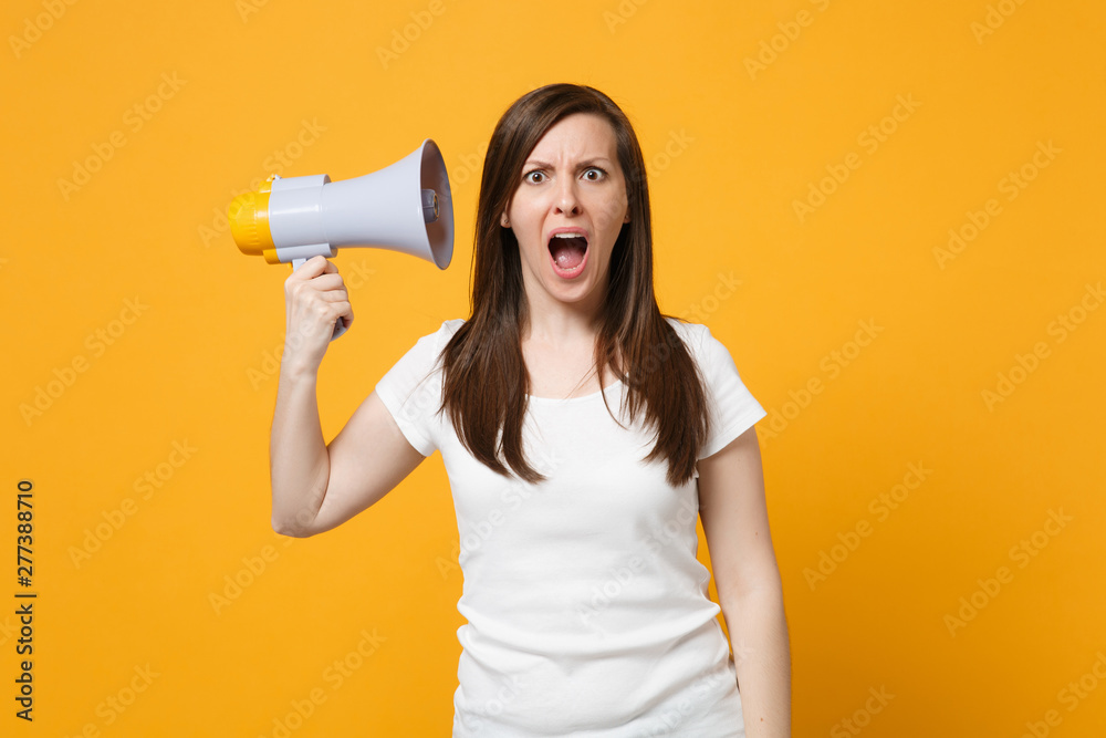 Portrait of shocked young woman in white casual clothes keeping mouth open, hold megaphone near ear isolated on bright yellow orange background in studio. People lifestyle concept. Mock up copy space. Portrait of shocked young woman in white casual clothes keeping mouth open, hold megaphone near ear isolated on bright yellow orange background in studio. People lifestyle concept. Mock up copy space.