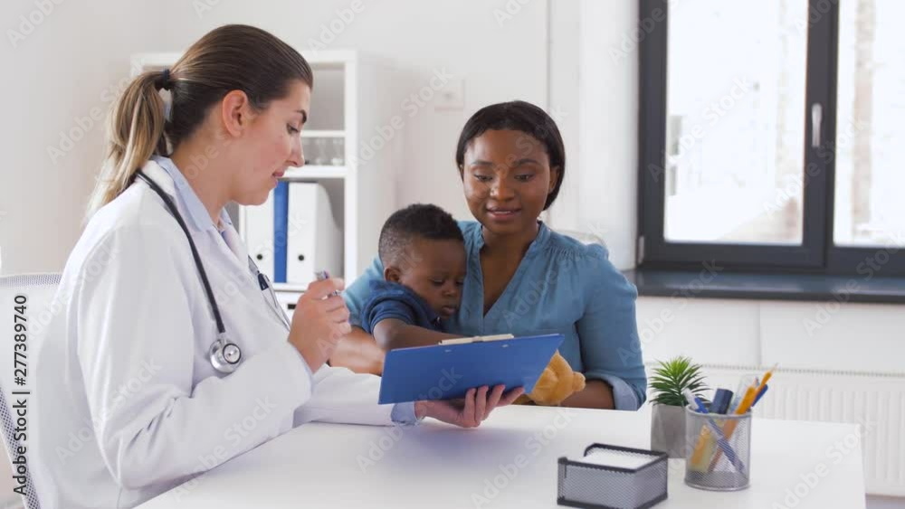 medicine, healthcare and pediatry concept - african american mother with baby son and caucasian doctor with clipboard at clinic medicine, healthcare and pediatry concept - african american mother with baby son and caucasian doctor with clipboard at clinic