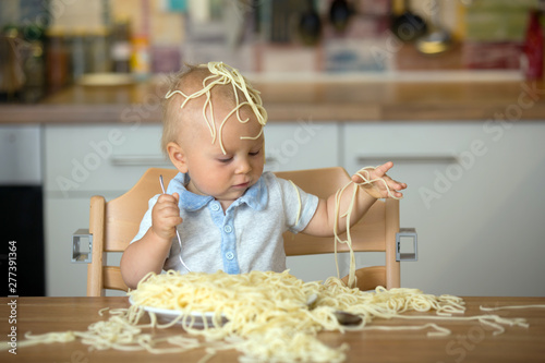 Little baby boy  toddler child  eating spaghetti for lunch and making a mess