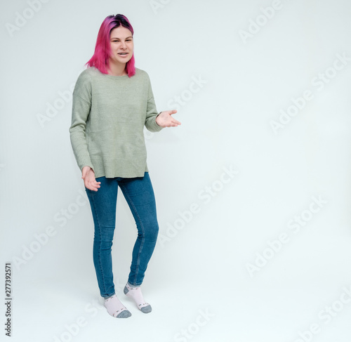 Full-length portrait of a young pretty teen girl with beautiful purple hair on a white background in the studio. Standing right in front of the camera, talking, smiling, showing hands with emotions.