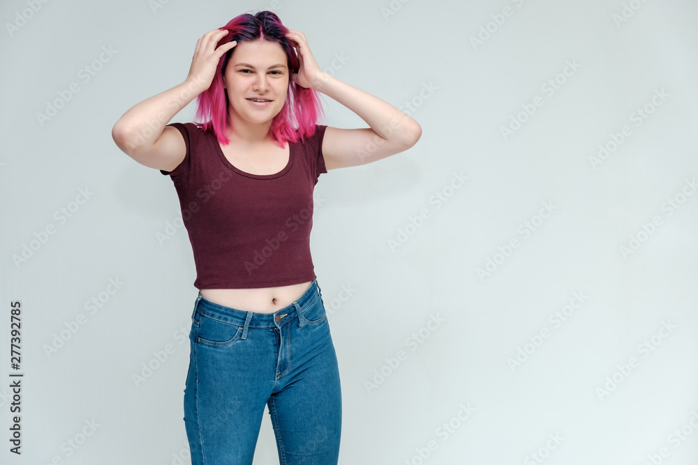 Full-length portrait of a young pretty teenager girl in jeans and a vest with beautiful purple hair on a white background in the studio. Talking, smiling, showing hands with emotions. Full-length portrait of a young pretty teenager girl in jeans and a vest with beautiful purple hair on a white background in the studio. Talking, smiling, showing hands with emotions.