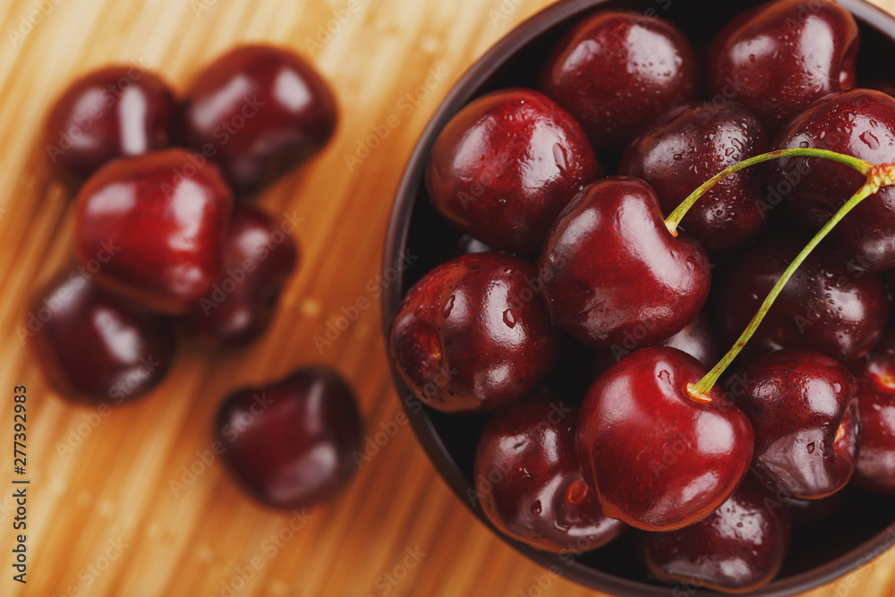 Ripe and juicy cherry berries on a wooden background in a brown cup Ripe and juicy cherry berries on a wooden background in a brown cup