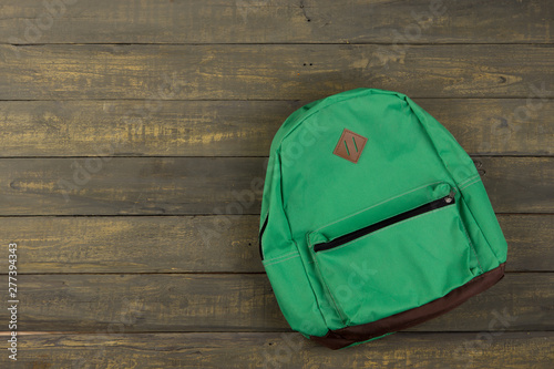 Back to school concept - green backpack on wooden backgroung,