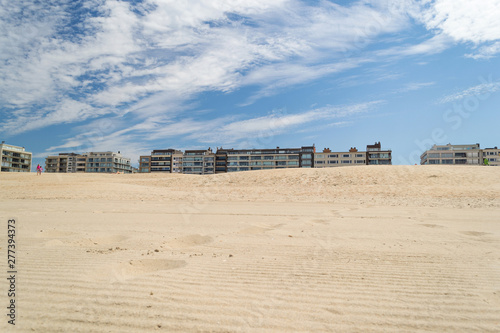 Immeubles de la digue d'Oostduinkerke qui surgissent de la dune. Eté ciel bleu sable chaud.
