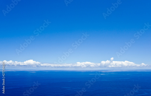 Ruhiges Meer, weiße Wolken und der Blick geht über den Horizont hinaus