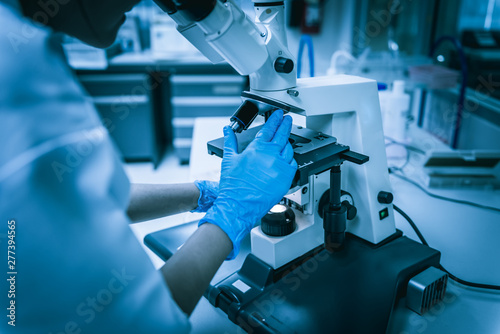 Young asian scientist looking through a microscope in a laboratory.Thailand people doing some research.