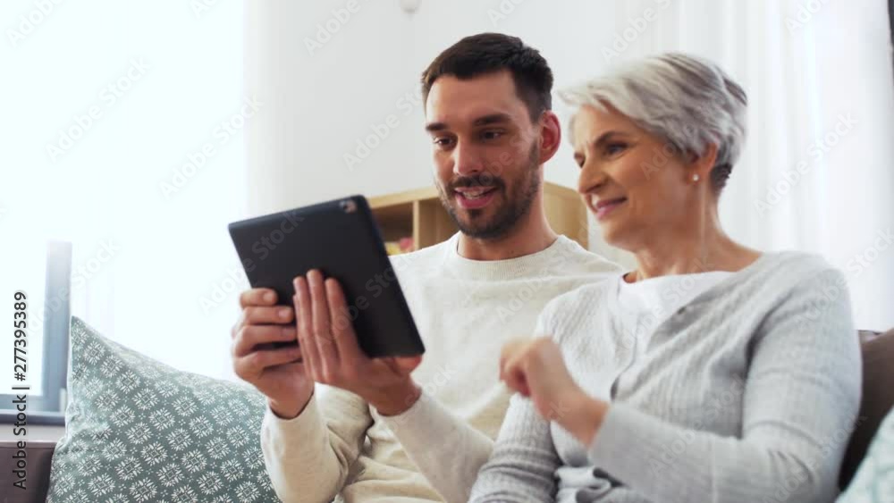 family, generation and technology concept - happy smiling senior mother and adult son with tablet computer at home family, generation and technology concept - happy smiling senior mother and adult son with tablet computer at home