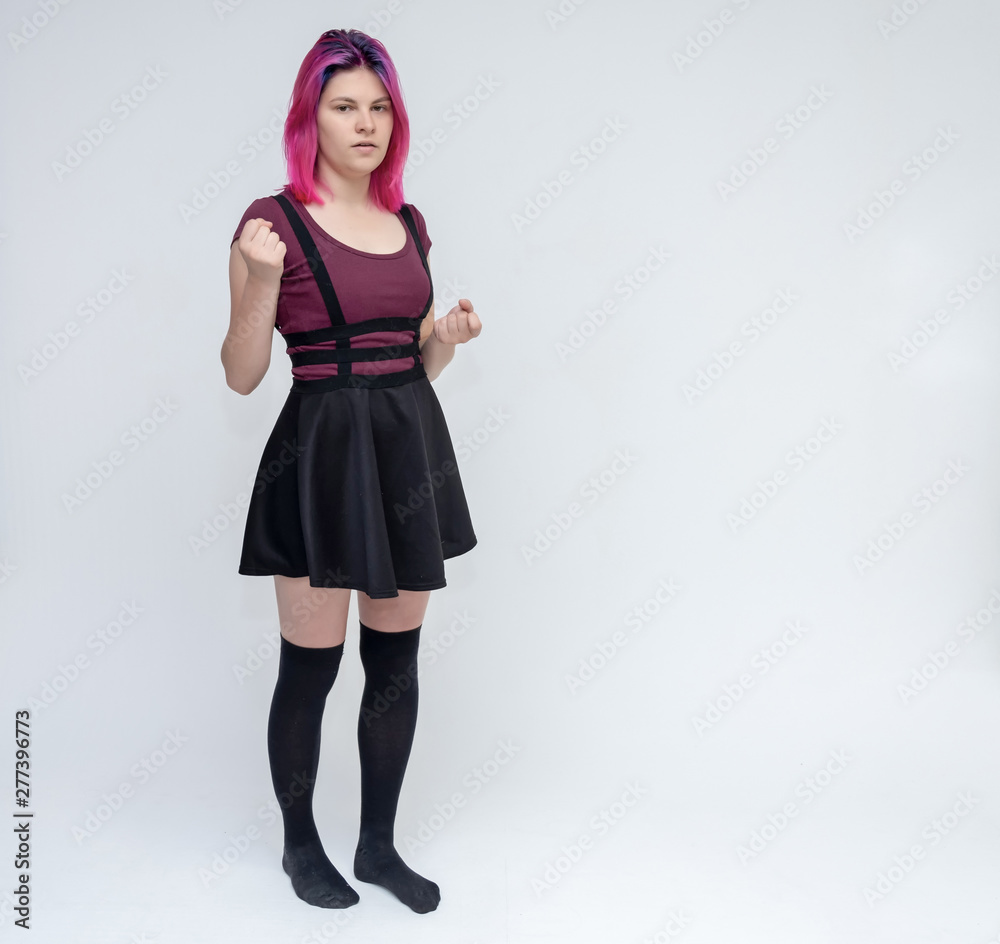 Full-length portrait of young pretty teenager girl in burgundy T-shirt and black dress with beautiful purple hair on a white background in the studio. Talking, smiling, showing hands with emotions. Full-length portrait of young pretty teenager girl in burgundy T-shirt and black dress with beautiful purple hair on a white background in the studio. Talking, smiling, showing hands with emotions.
