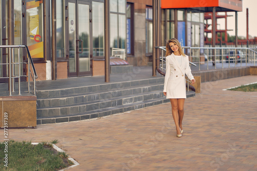 slim girl in a white coat walk around the city. copy space © Aleksandr