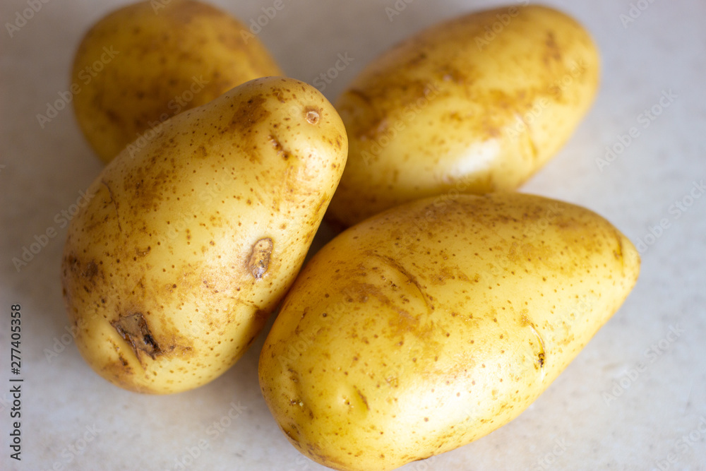 Studio macro of stacked potatoes with soft shadows on a white surface. Copy space. Golden brown potatoes on white surface. Golden round potatoes on a white surface Studio macro of stacked potatoes with soft shadows on a white surface. Copy space. Golden brown potatoes on white surface. Golden round potatoes on a white surface