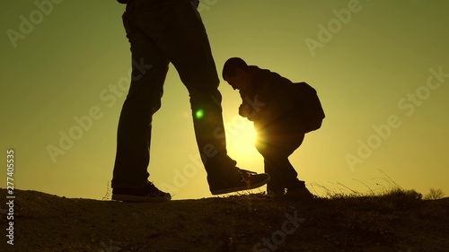 three travelers descend from hill in rays of sun one after other go beyond horizon. teamwork of business people. tourists travel with backpacks. business team is in hurry to win.