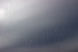 Close up shot of rain drops on glass window against sunset. Raindrops on window against a light background. Raindrops on the window