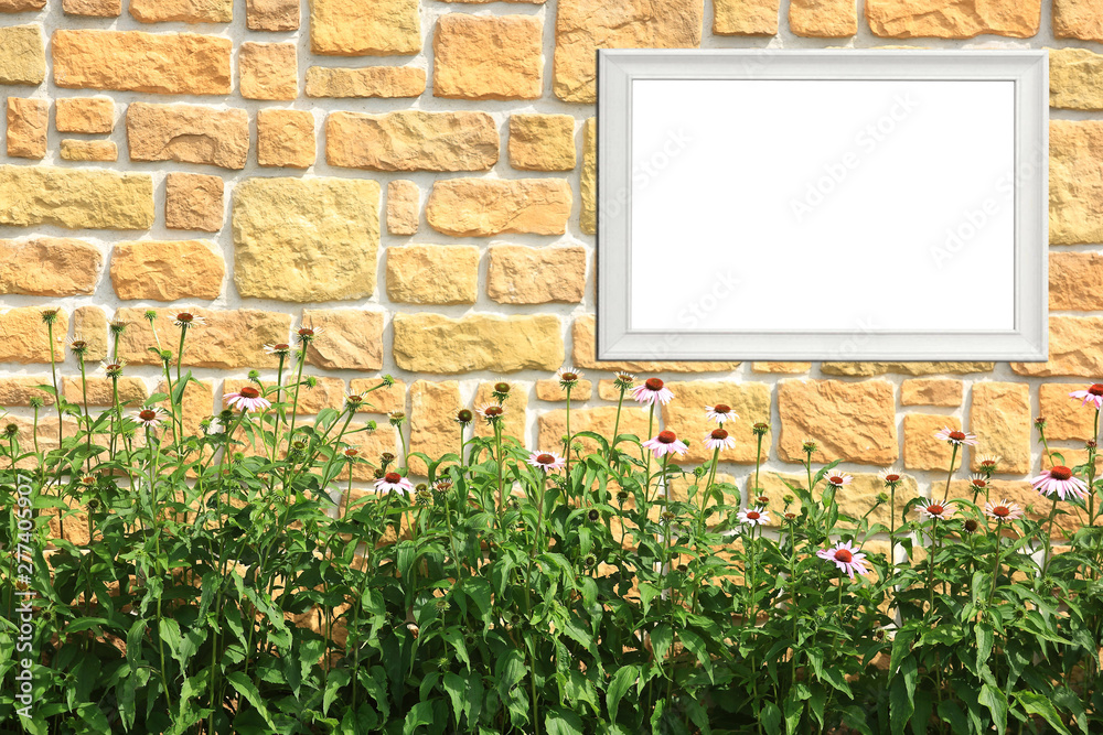 Fototapeta premium Biały szyld reklamowy na kamiennej ścianie, tekst, napis, kolorowe kwiaty.