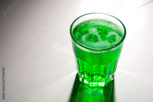 glass with green soda on a white background