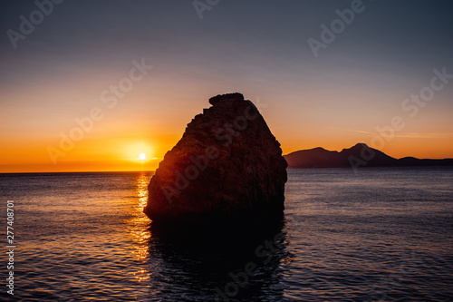 Rock island in the ocean water with colorful sunset at the mediterreanean sea and calm sea water. Port d' Andratx, Port Andratx, Mallorca Spain Balearics photo