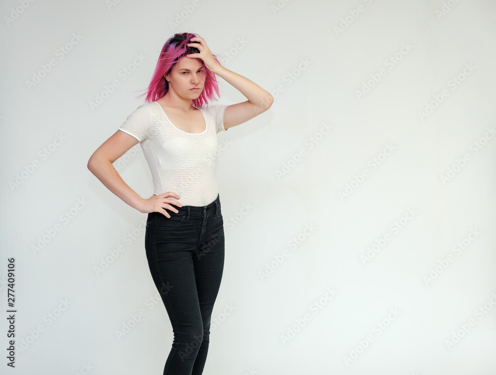 Portrait below the knee of a young beautiful girl teenager in a white T-shirt and black jeans with beautiful purple hair on a white background in the studio. They say, they smile, they show hands Portrait below the knee of a young beautiful girl teenager in a white T-shirt and black jeans with beautiful purple hair on a white background in the studio. They say, they smile, they show hands
