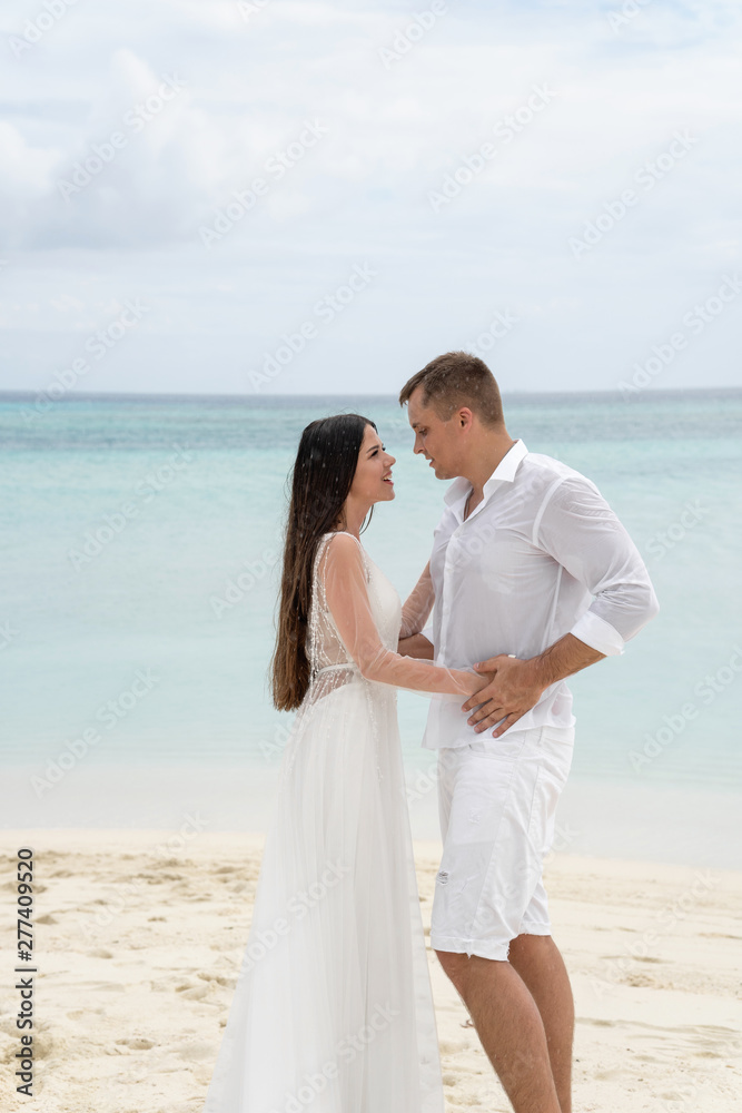 Newlyweds are hugging on a gorgeous beach with white sand and turquoise water. Newlyweds are hugging on a gorgeous beach with white sand and turquoise water.