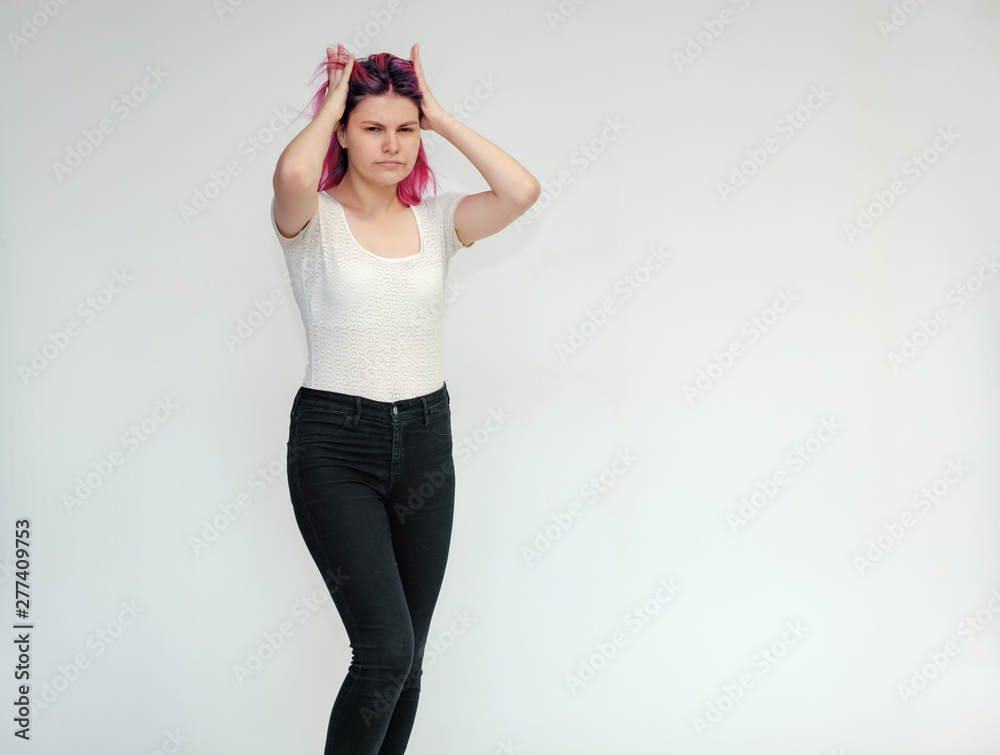 Portrait below the knee of a young beautiful girl teenager in a white T-shirt and black jeans with beautiful purple hair on a white background in the studio. They say, they smile, they show hands Portrait below the knee of a young beautiful girl teenager in a white T-shirt and black jeans with beautiful purple hair on a white background in the studio. They say, they smile, they show hands