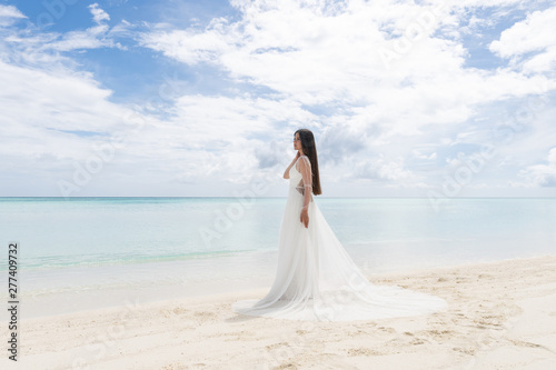 The perfect bride. A young bride in a white dress is standing on a snow-white beach.