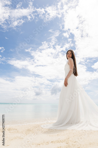 The perfect bride. A young bride in a white dress is standing on a snow-white beach.