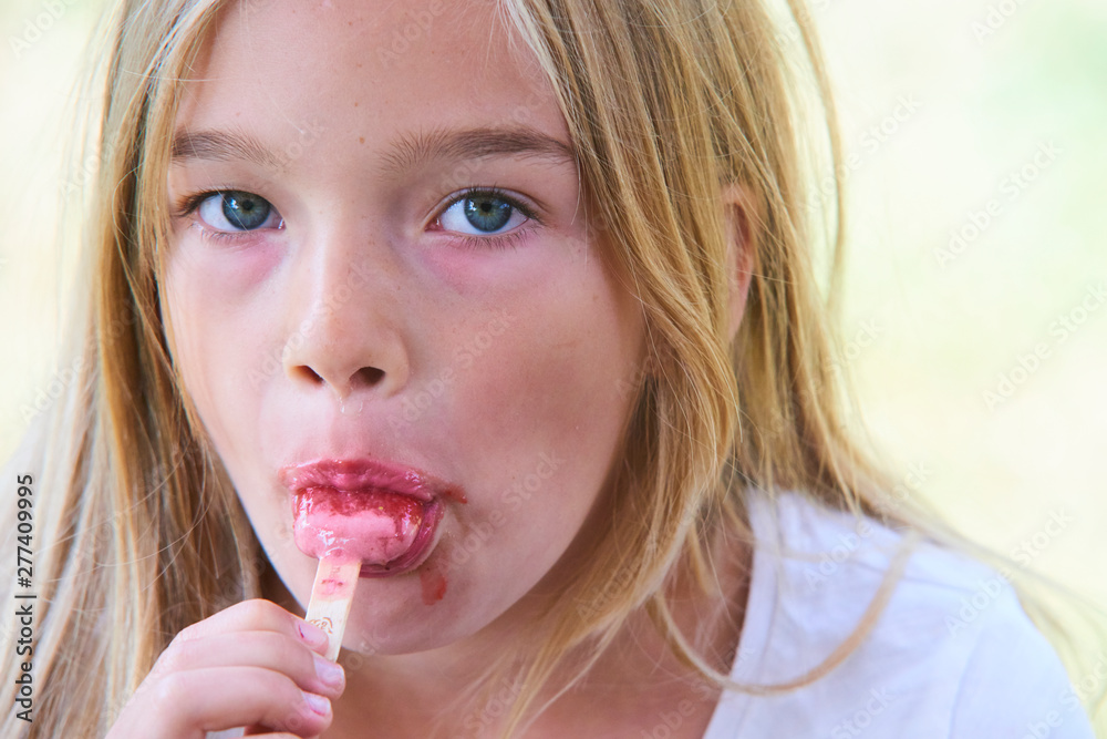 Beautiful little girl eats strawberry ice-cream in the summer. Selective focus Beautiful little girl eats strawberry ice-cream in the summer. Selective focus