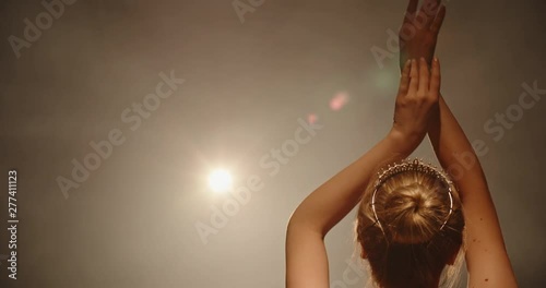 Beautiful caucasian ballet dancer performing, dancing and spinning on stage, spotted by searchlight andisolated on smoked black background close up 4k footage photo