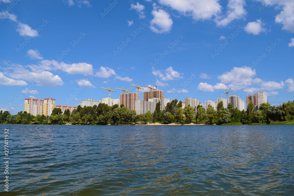 View across the lake to the green forest and houses in the city.