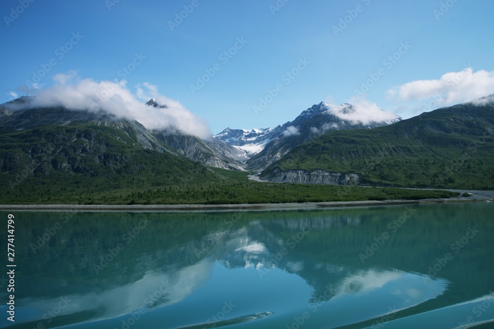 Reflection of rugged mountains in the still ocean water of Glacier Bay