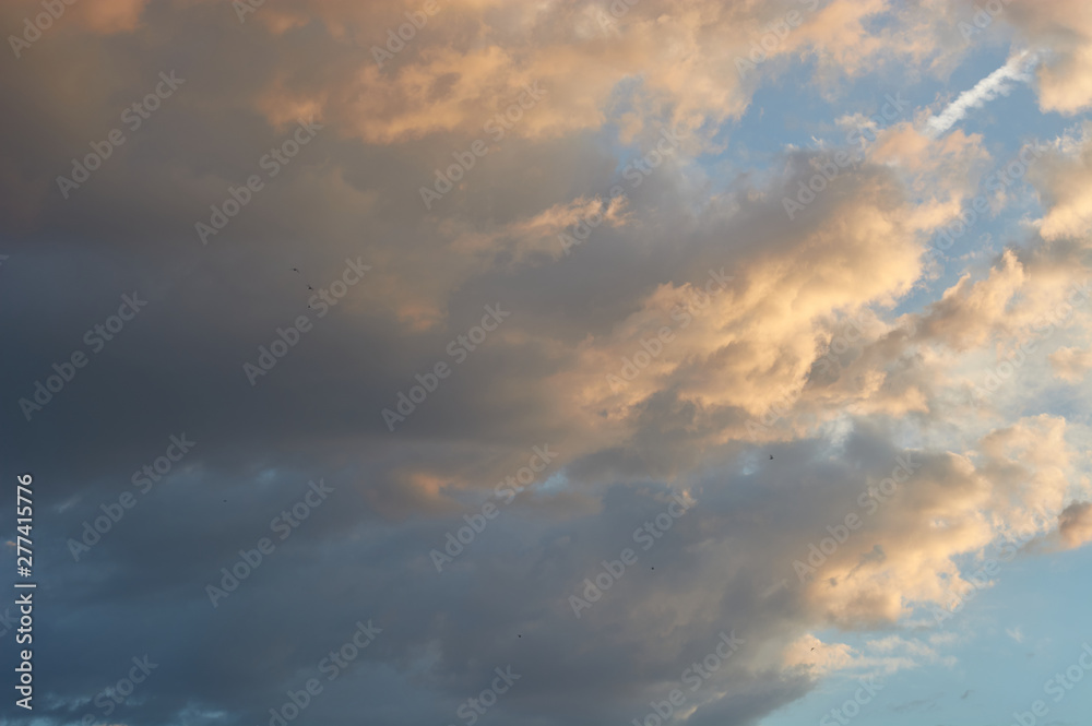 Blue sky with clouds at sunset, illuminated by the sun